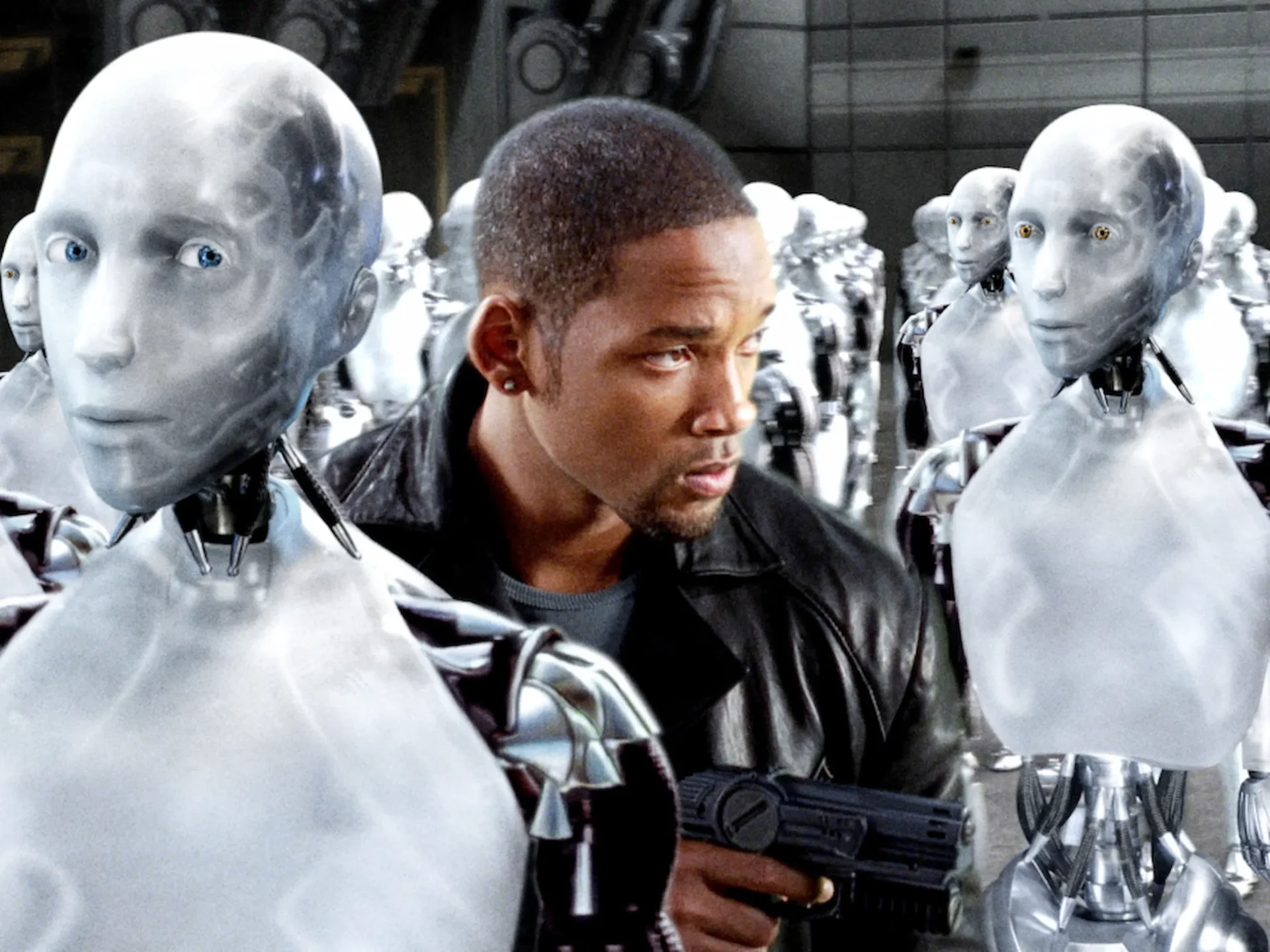 Man in a black jacket surrounded by tall silver humanoid robots with blue eyes in a sci-fi setting