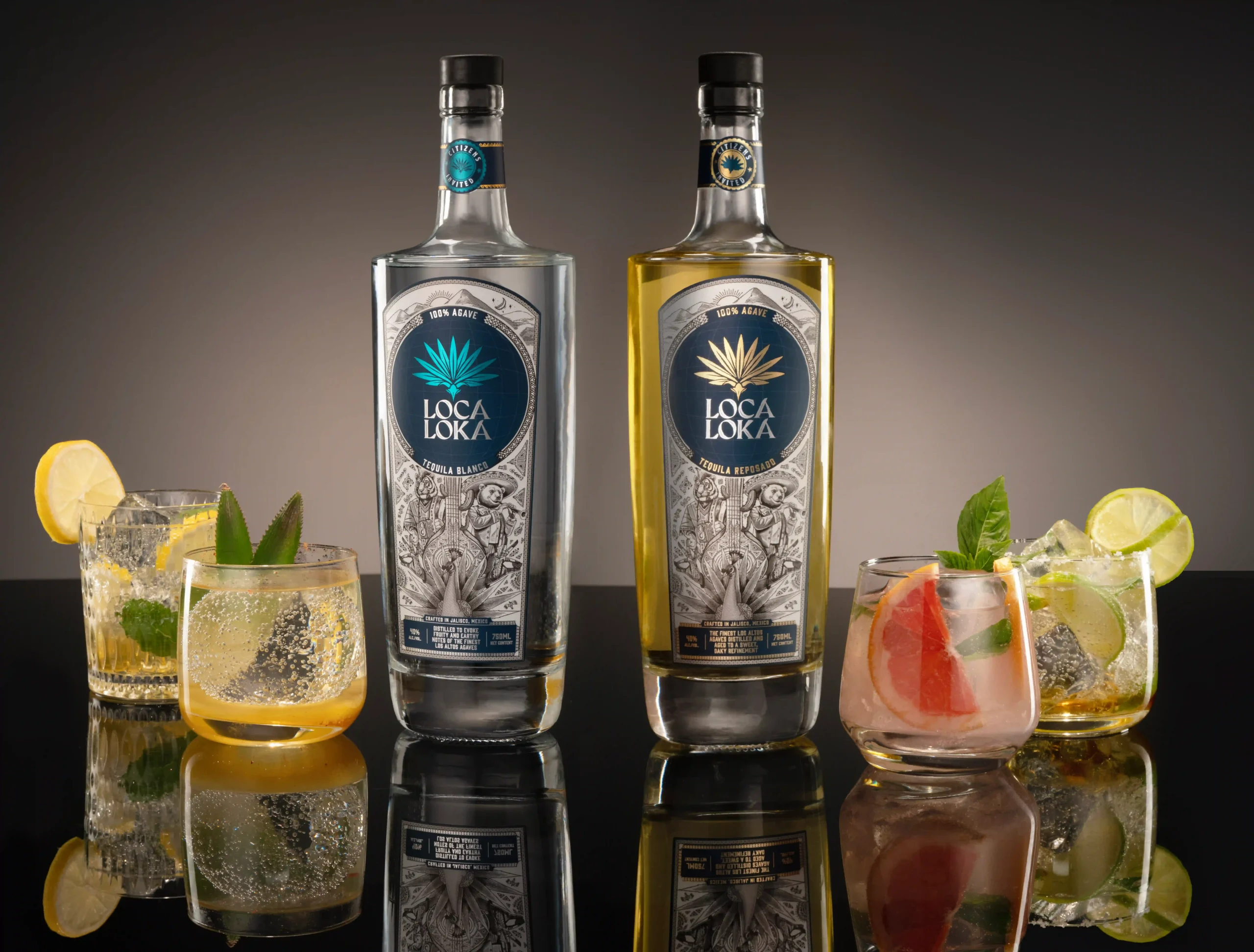 Two Loca Loka tequila bottles (blanco and reposado) on a bar with citrus cocktails and ice.