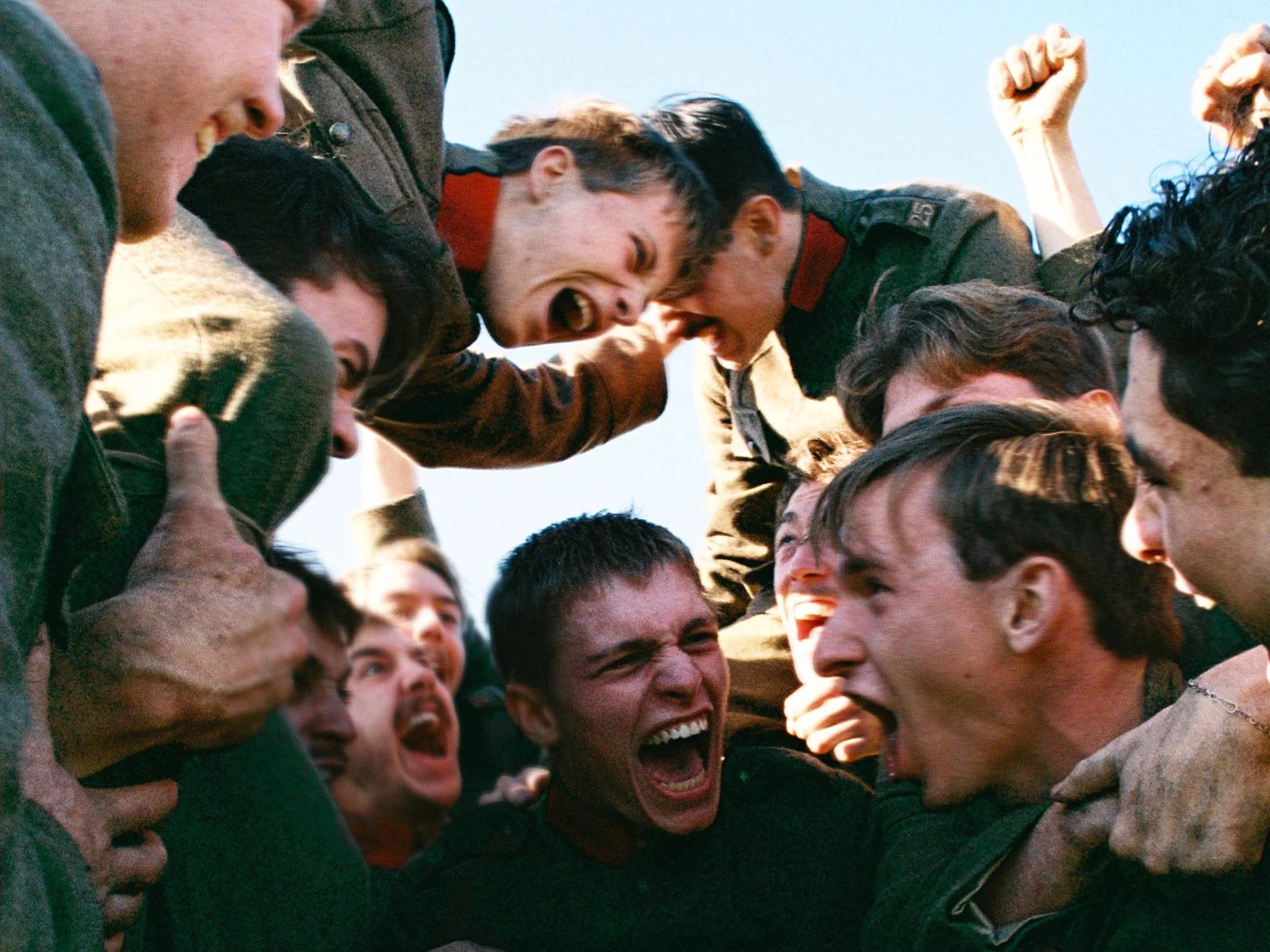 Group of friends in a tight circle, arms raised, smiling and cheering together.